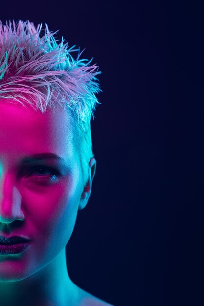 Portrait of female fashion model in neon light on dark.