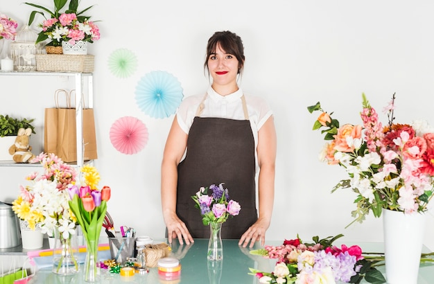 机の上に花の花瓶を持つ女性の花屋の肖像