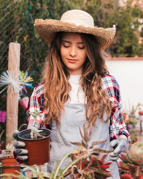 Foto gratuita ritratto di un giardiniere femminile che tiene pianta di cactus in vaso