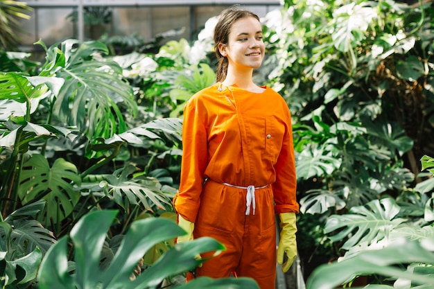 Ritratto di un giardiniere femminile in abiti da lavoro in piedi in serra