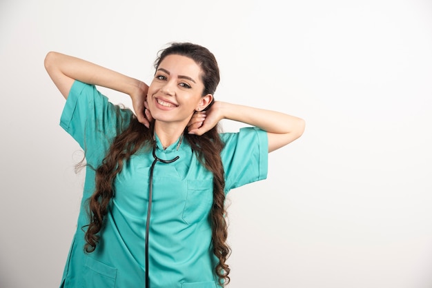 Portrait of female healthcare worker posing on white wall.