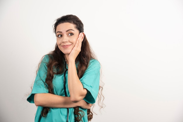 Portrait of female healthcare worker posing on white wall.