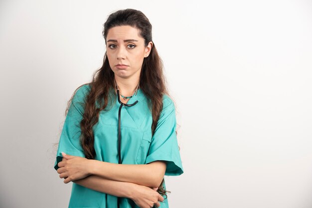 Portrait of female healthcare worker posing on white wall.