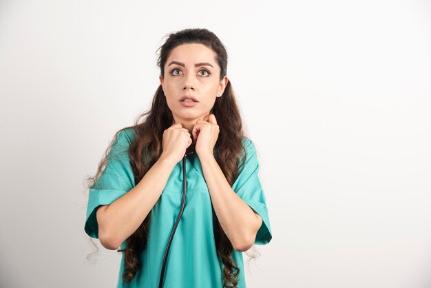 Portrait of female healthcare worker posing on white wall.