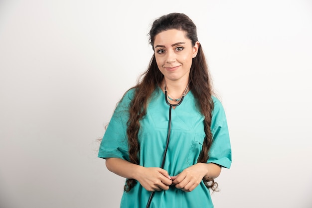 Portrait of female healthcare worker posing on white wall.