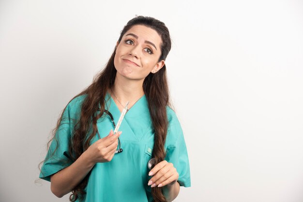 Portrait of female healthcare worker posing with thermometer.
