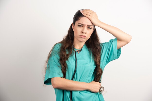 Portrait of female healthcare worker touching her head and stomach.