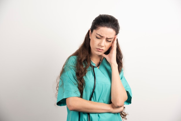 Portrait of female healthcare worker touching her head.