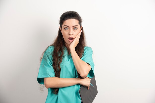 Portrait of female healthcare worker on white wall.