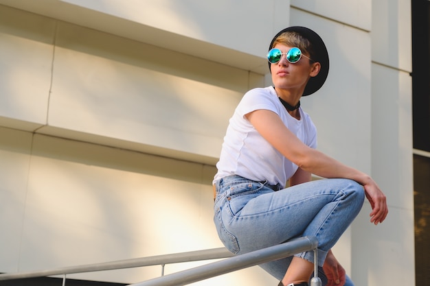 Free photo portrait of female hipster with natural makeup and short haircut enjoying leisure time outdoors