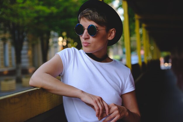 Portrait of female hipster with natural makeup and short haircut enjoying leisure time outdoors