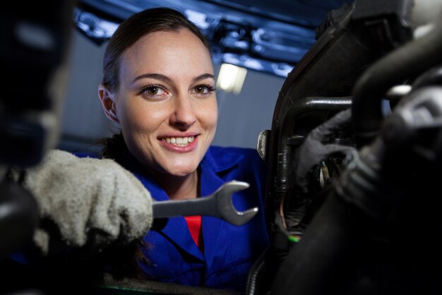 Portrait of female mechanic examining car engine