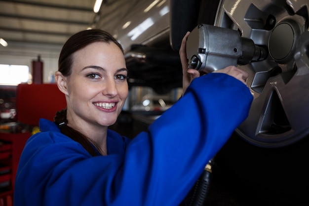 Foto gratuita ritratto di meccanico femminile fissare una ruota auto