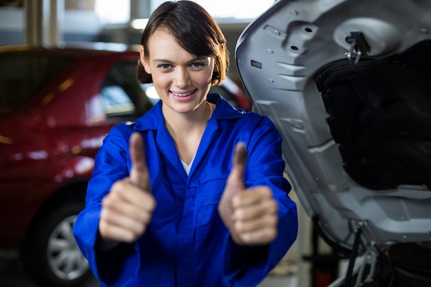 Portrait of female mechanic showing thumbs up