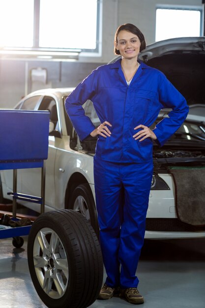 Portrait of female mechanic standing with a tyre