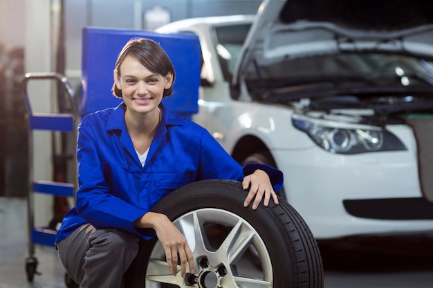 Portrait of female mechanic with a tyre