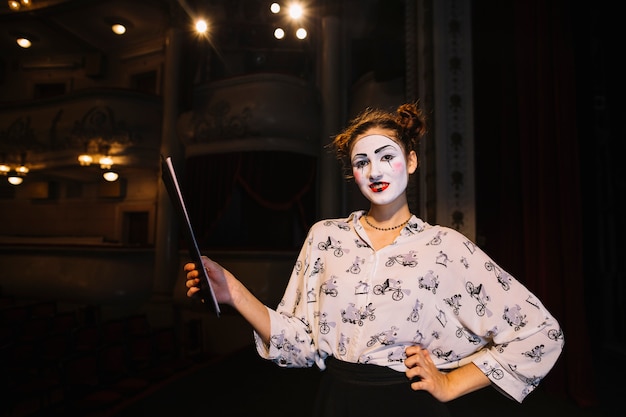 Portrait of female mime holding script standing on stage