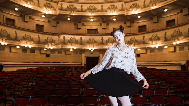 portrait of female mime standing in an auditorium posing