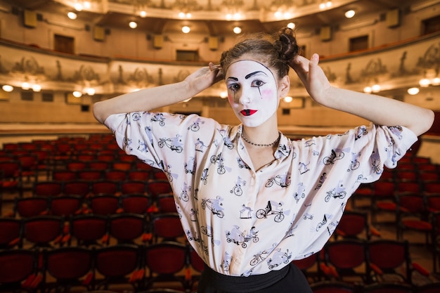 Portrait of female mime standing in an auditorium