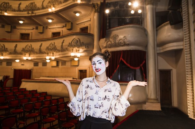 Portrait of female mime standing on stage shrugging