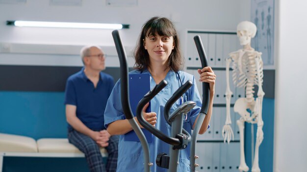 Portrait of female nurse standing in medical cabinet, getting ready to help patients, to do physical therapy procedure. Health specialist working in health care system to cure disease.