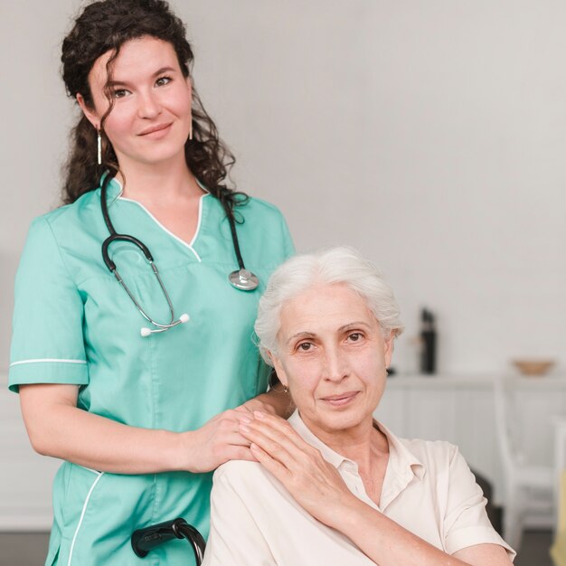 Портрет женщины-медсестра с ее старшим пациентом, сидящим на инвалидной коляске