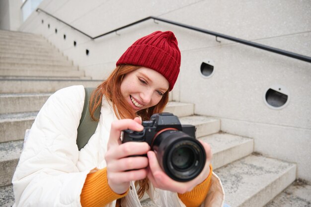 Portrait of female photographer walking around city with professional camera taking pictures capturi