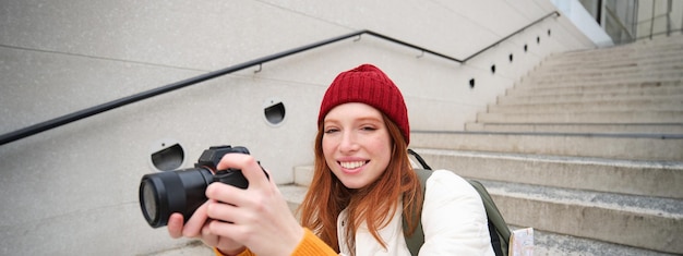 Portrait of female photographer walking around city with professional camera taking pictures