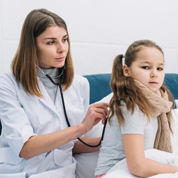 Portrait of a female physician examining the girl's patient suffering from the cold