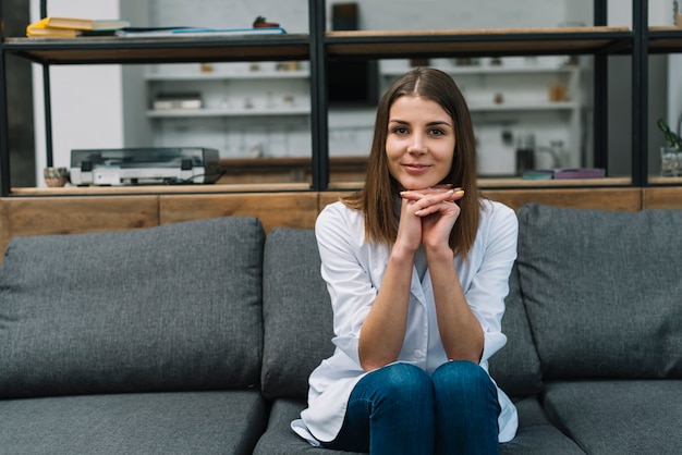 Free photo portrait of a female physician sitting on gray sofa with hand clasped