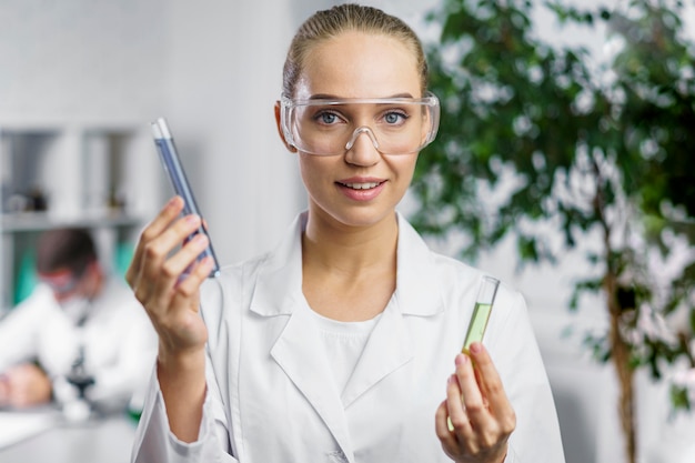 Foto gratuita ritratto di ricercatore femminile in laboratorio con occhiali di sicurezza e provette