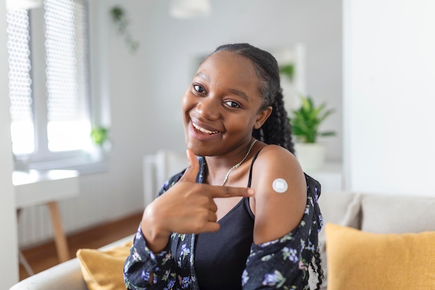 Free photo portrait of a female smiling after getting a vaccine woman holding down her shirt sleeve and showing her arm with bandage after receiving vaccination