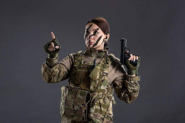 Free photo portrait of female soldier in camouflage with gun dark wall