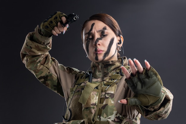 暗い壁に銃を持った軍服の女性兵士の肖像画