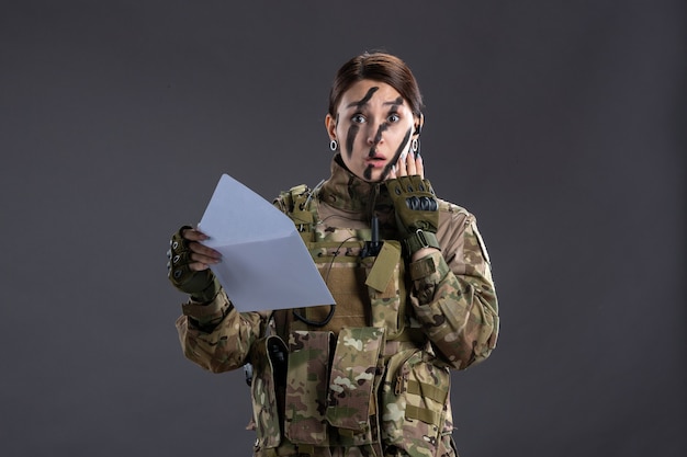 어두운 벽에 편지를 읽는 여성 군인의 초상화