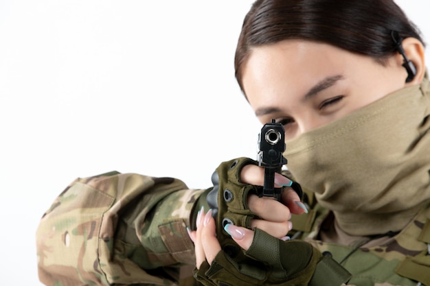 迷彩の白い壁に銃を持った女性兵士のポートレート