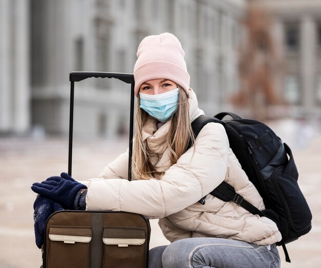 Portrait female student wearing mask and carrying luggage