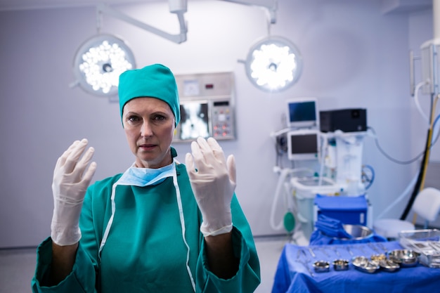 手術室で手術用手袋を着用している女性外科医の肖像画