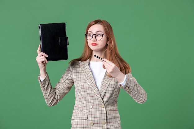 Portrait of female teacher holding notepad on green