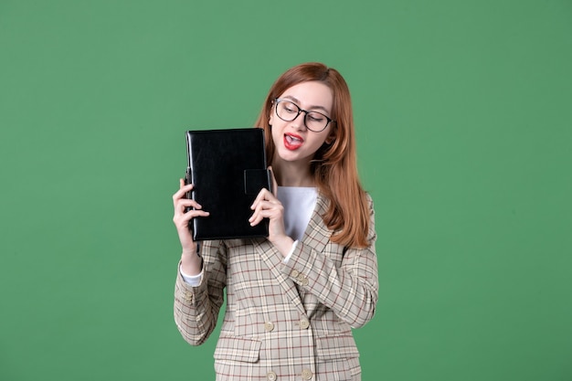 Портрет учительницы, держащей блокнот на зеленом