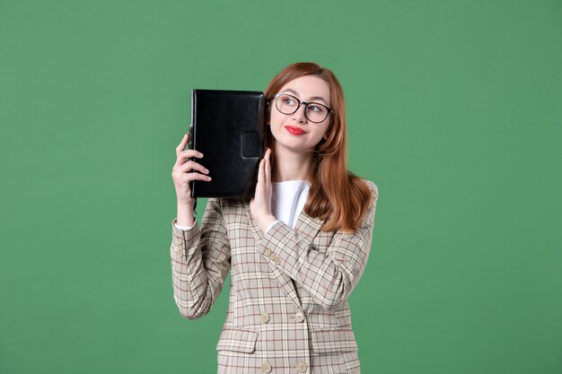 Портрет учительницы, держащей блокнот на зеленом