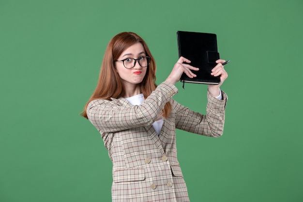 Portrait of female teacher holding notepad on green