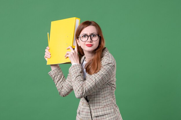 Портрет учительницы, держащей желтый документ на зеленом