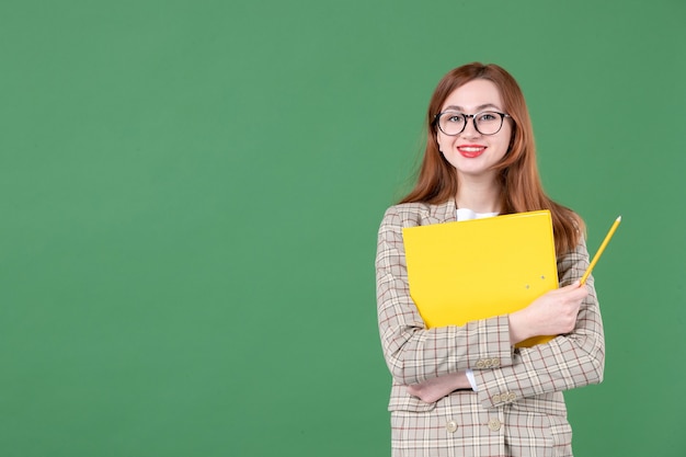 緑に幸せな黄色のドキュメントを保持している女教師の肖像画