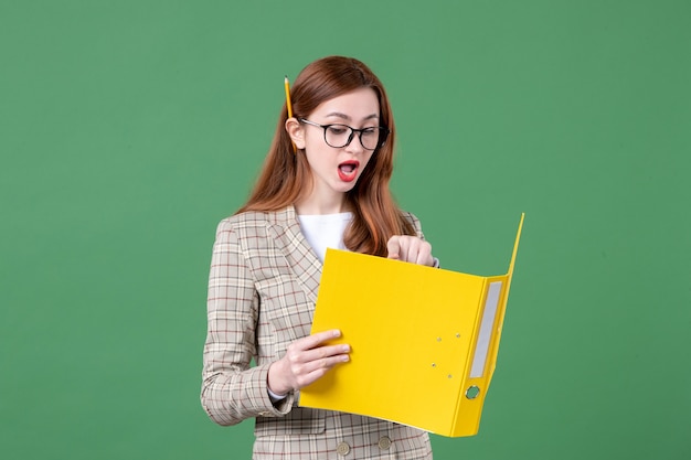 Ritratto di insegnante femminile che legge documento giallo su green