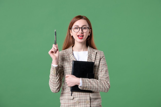 Portrait of female teacher in suit on green