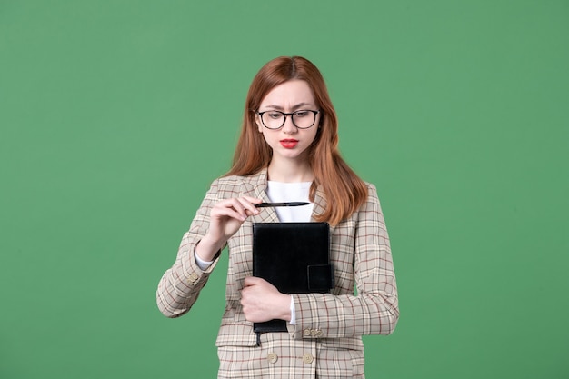 Free photo portrait of female teacher in suit with notepad on green