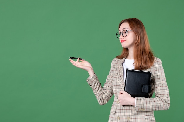 Portrait of female teacher with notepad on green