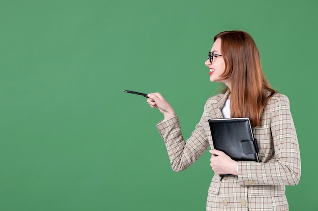 Portrait of female teacher with notepad on green