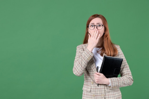 Ritratto di insegnante femminile con blocco note sorpreso su green